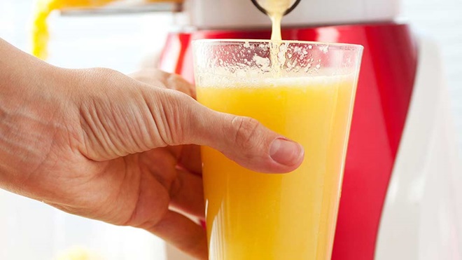 orange juice pouring from juicer